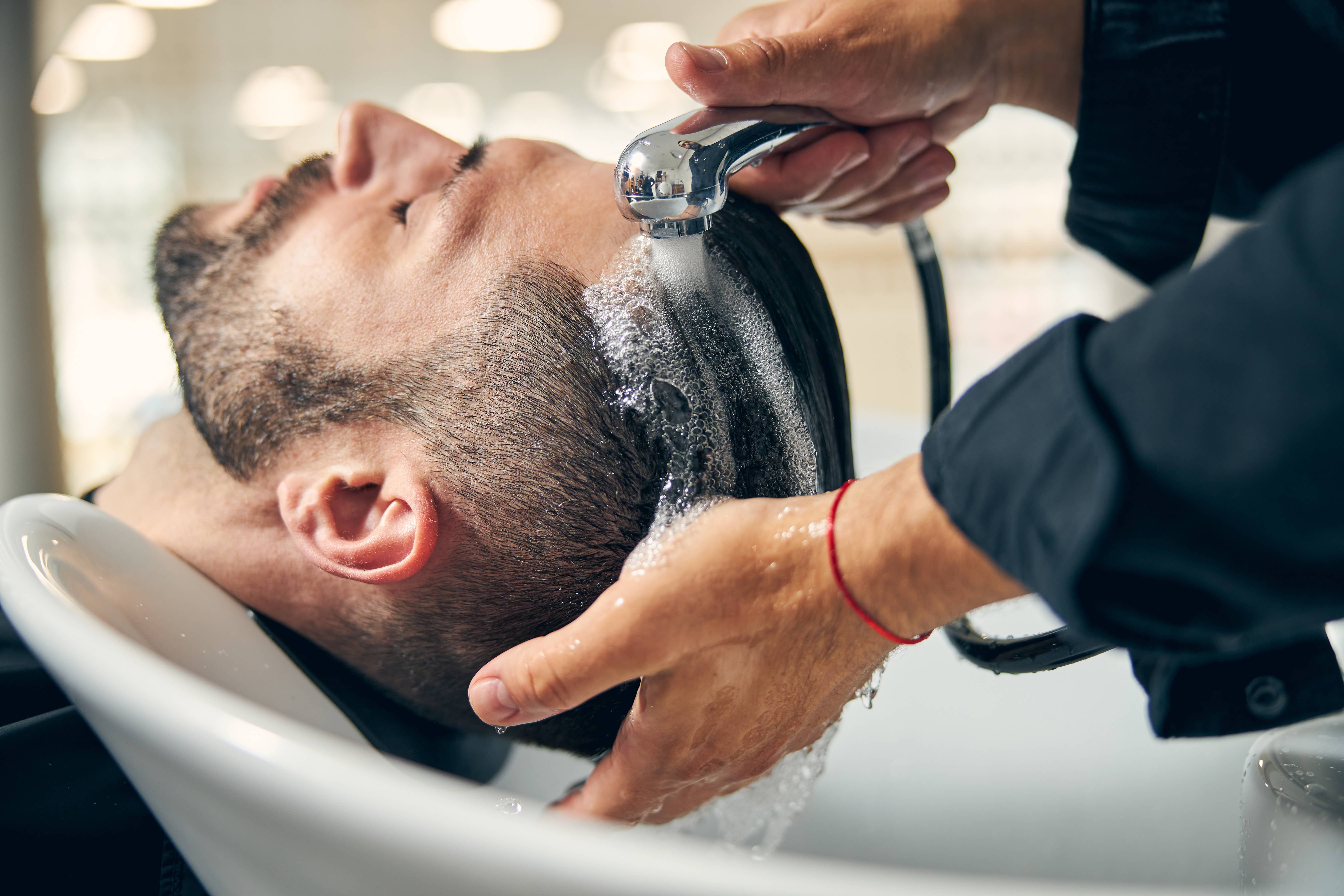 Homme à qui on lave les cheveux Homme à qui on lave les cheveux